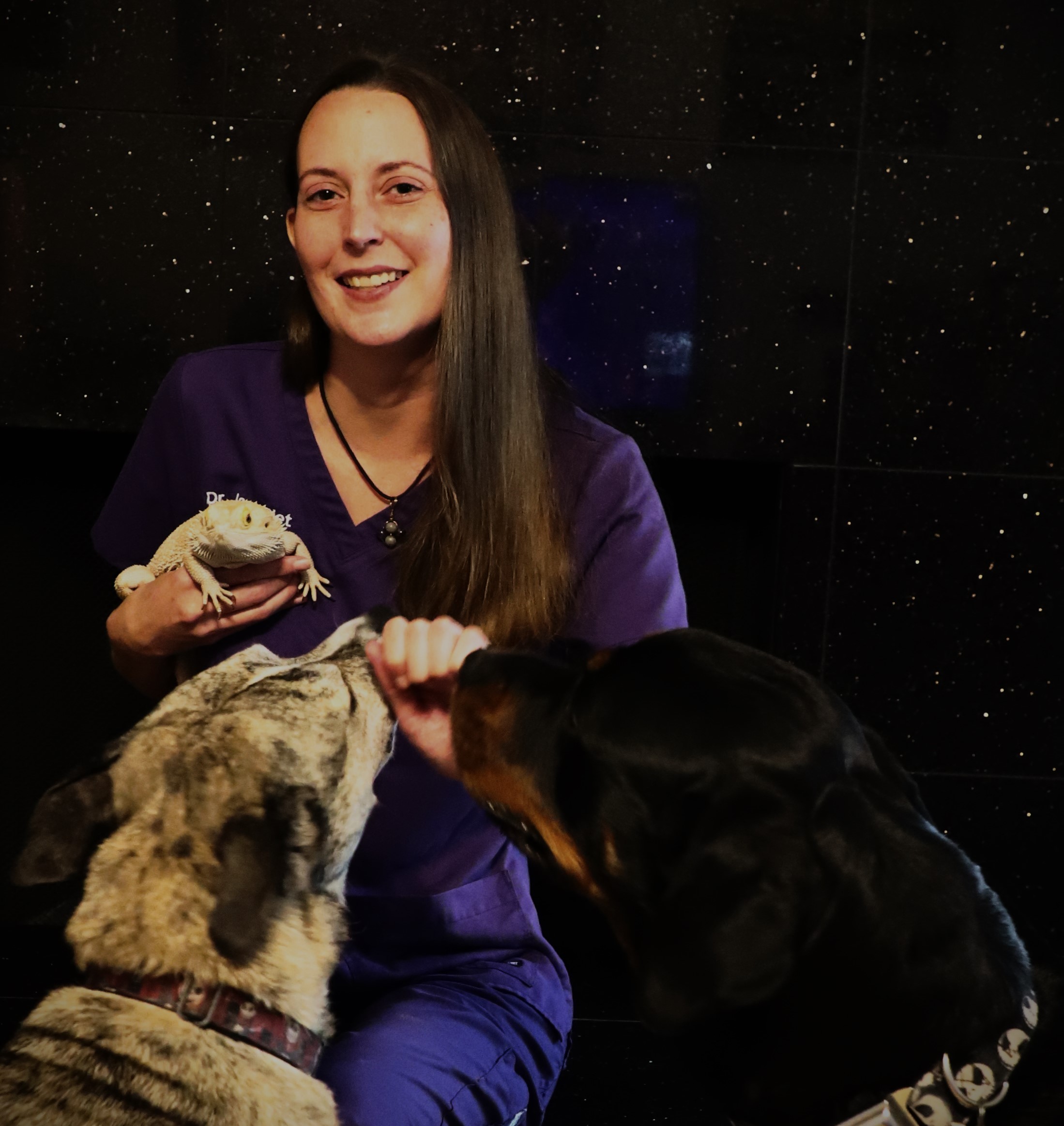 Dr. Jacci Piet together with pets in a dark background.